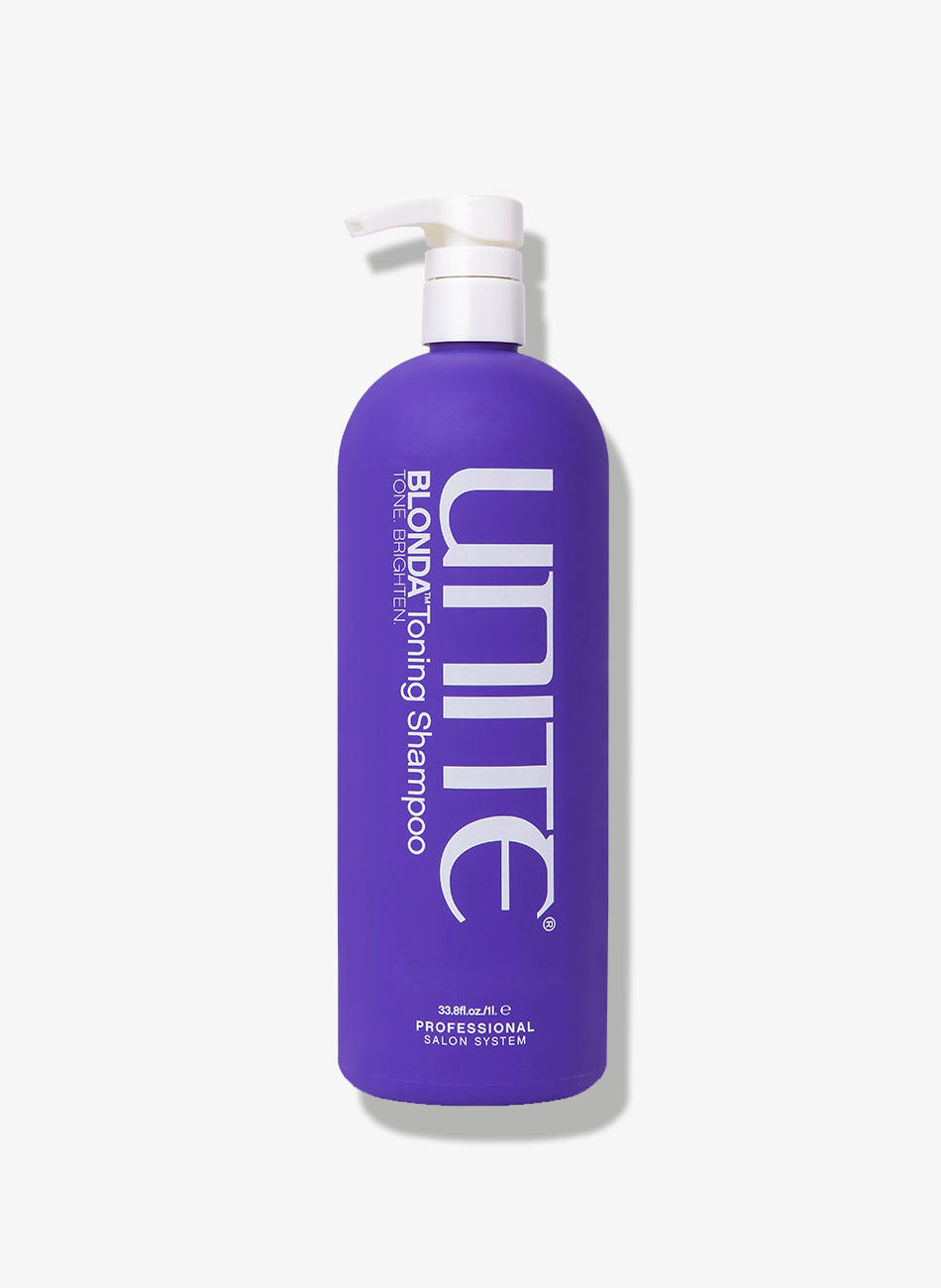 Large bottle of violet shampoo with pump dispenser for professional salon use.