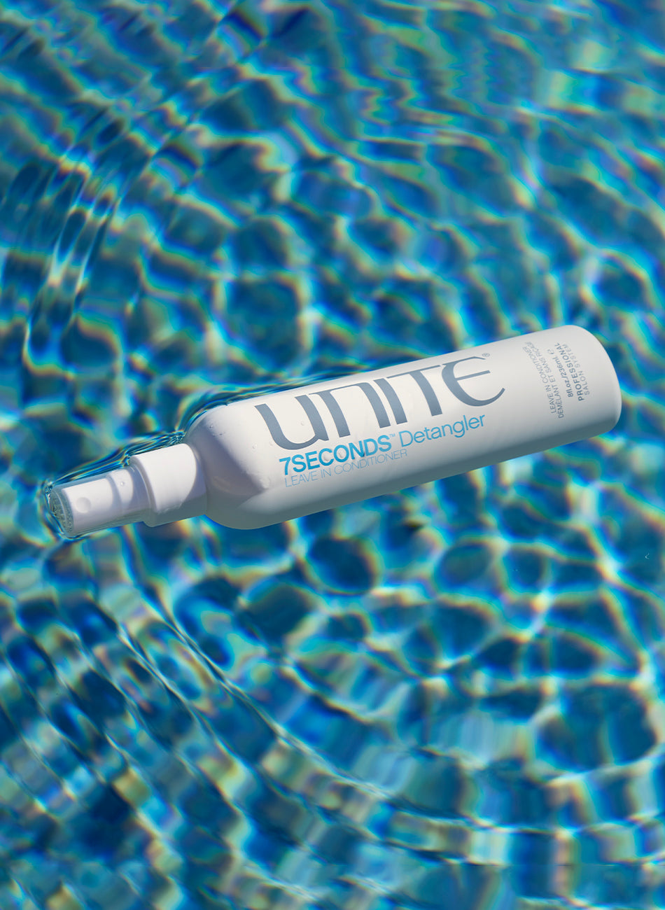 UNITE 7SECONDS hair detangler leave-in conditioner bottle floating in a pool with rippling blue water.