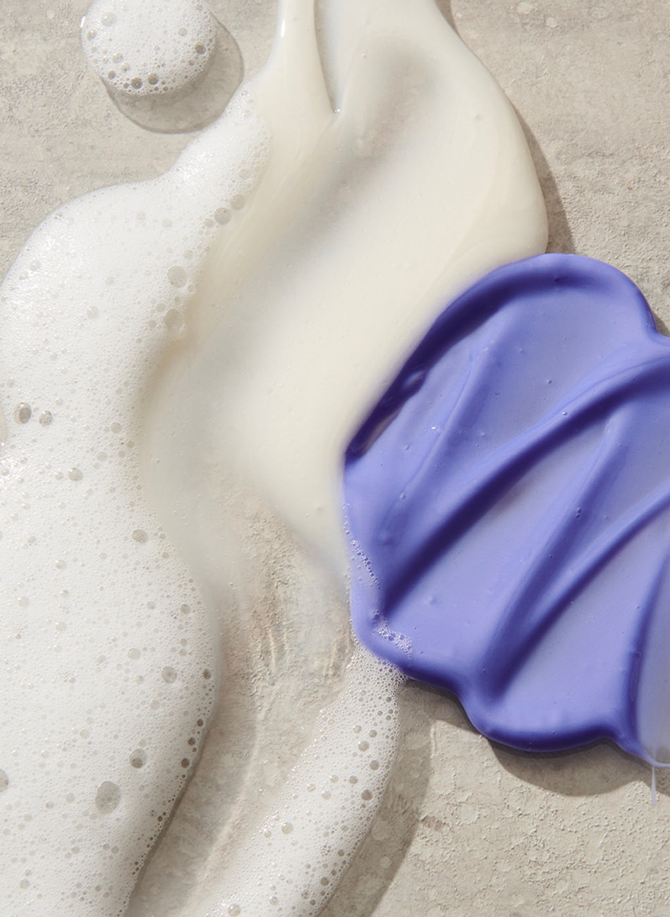 Purple conditioner and shampoo textures on a surface.